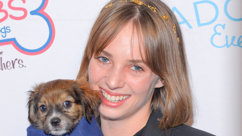 Maya Hawke smiling with a dog