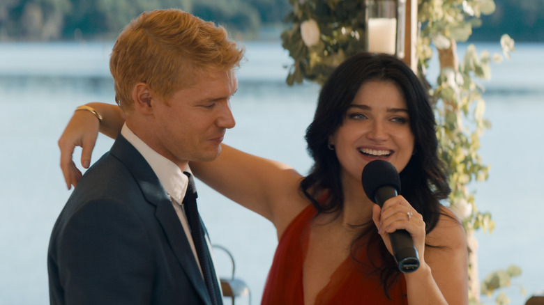 Amelia with her arm around Benji while she talks into mic in "The Perfect Couple"