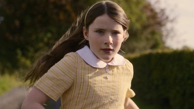 Cáit runs in a yellow and white dress in "The Quiet Girl" (2023)