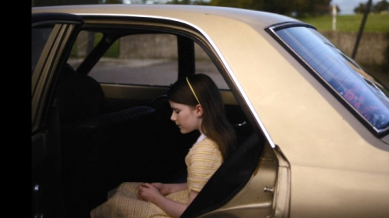 Cáit sits in a yellow car in "The Quiet Girl" (2023)