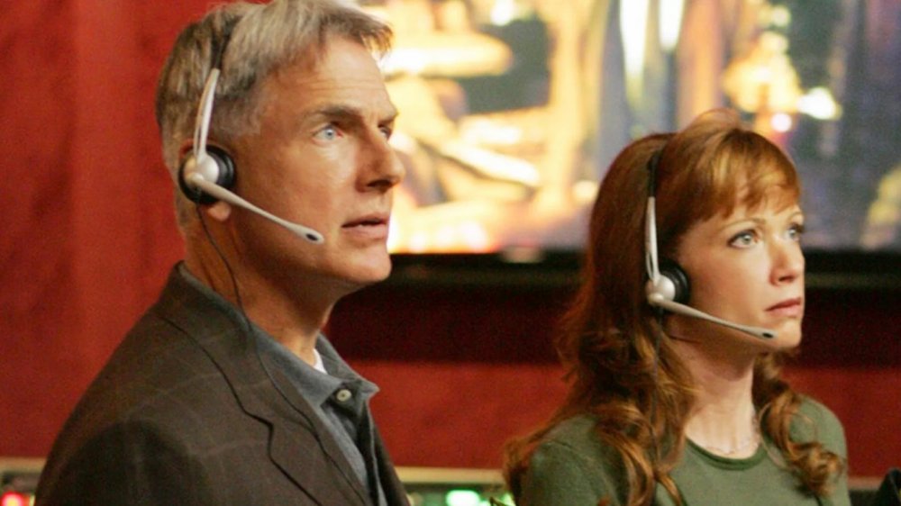 Mark Harmon as Agent Gibbs and Lauren Holly as Director Jenny Shepard wear headphones with microphones in NCIS