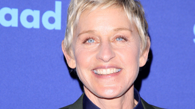 Ellen DeGeneres smiling against blue background