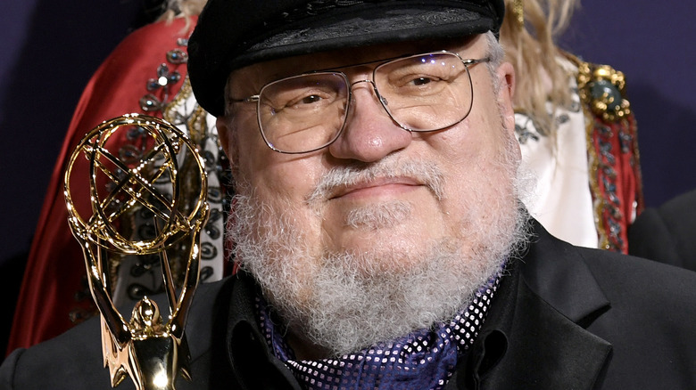 George R.R. Martin smiling and holding an Emmy