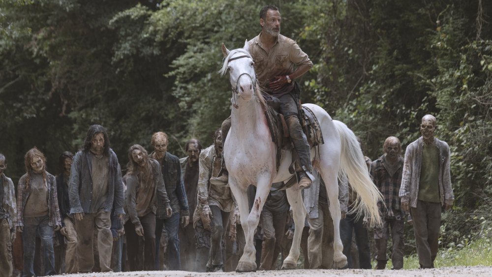 Rick Grimes on a horse being followed by walkers on The Walking Dead