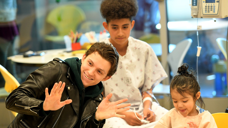 Tom Holland visiting children in a hospital and waving