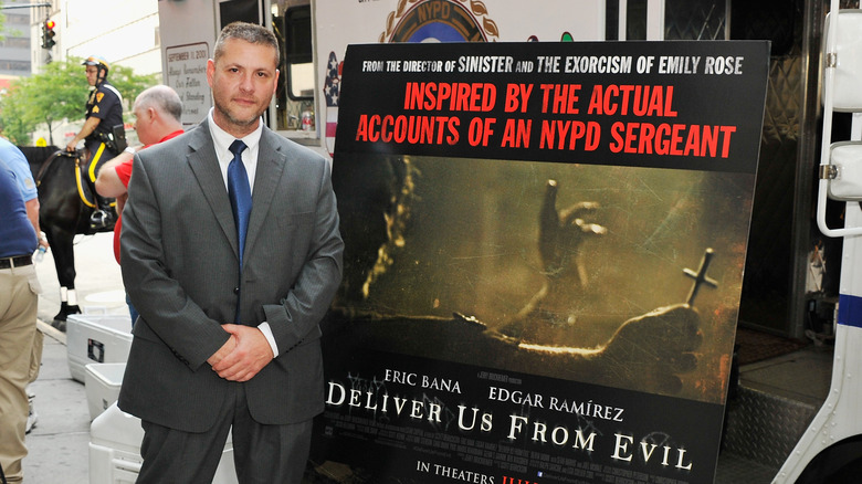 Ralph Sarchie stands beside a poster for "Deliver Us from Evil" (2014)