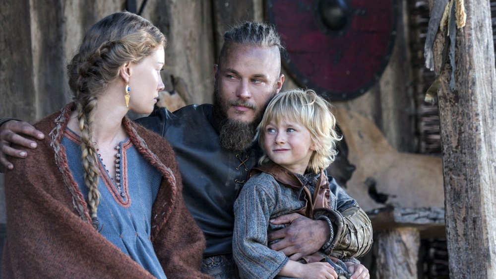 Alyssa Sutherland as Aslaug sitting with Travis Fimmel as Ragnar and James Quinn Markey as their young son Ivar on Vikings