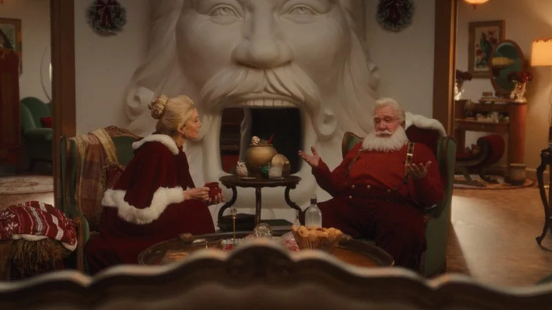 Santa Claus and Mrs. Claus talking by the fireplace