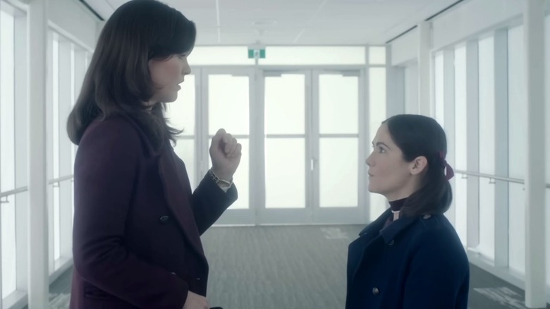 Tricia and Leena stand in a brightly-lit hallway, facing each other