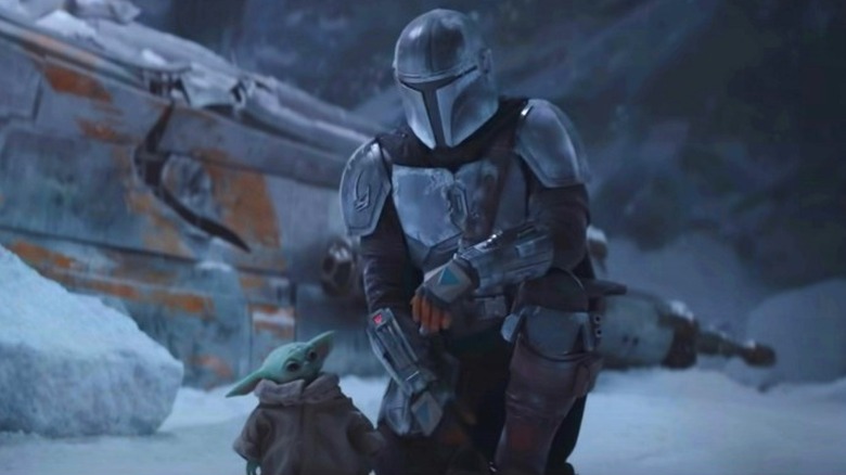 The Mandalorian kneeling next to Grogu