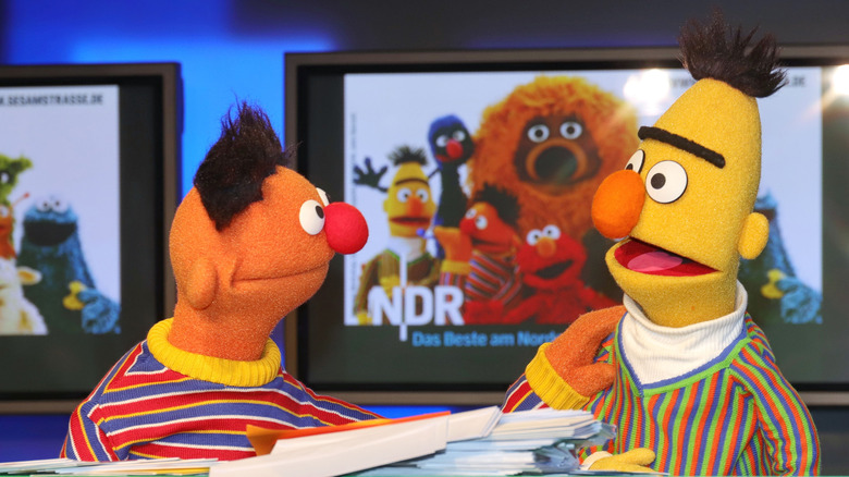 Bert and Ernie talk near Sesame Street poster