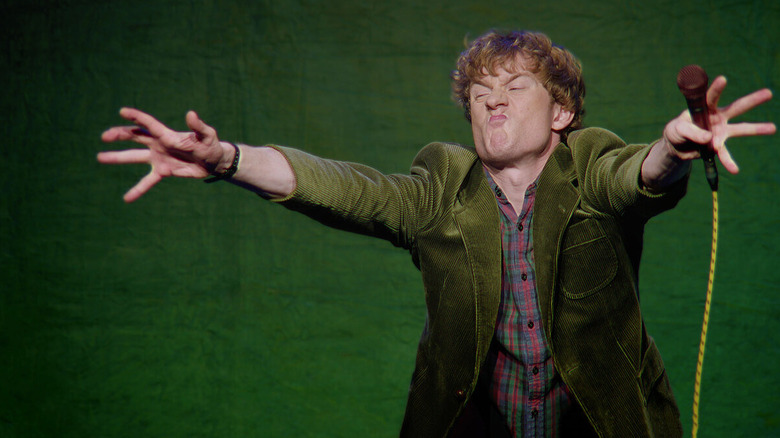 James Acaster grimacing on stage