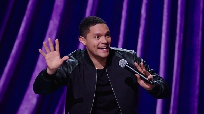 Trevor Noah laughing on stage