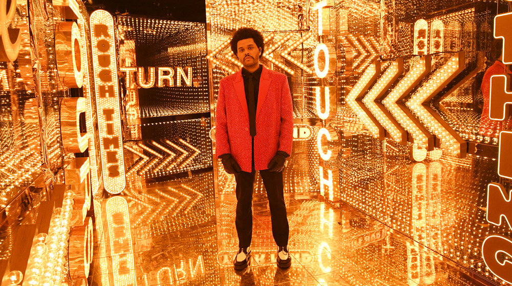 The Weeknd stands in lit up gold room