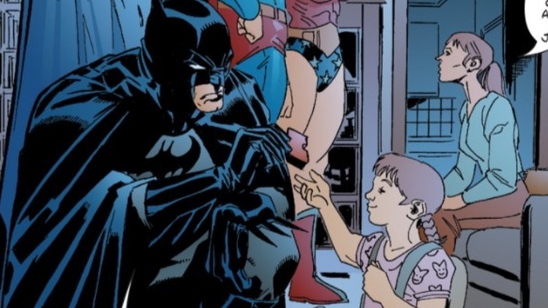 Batman offering a puzzle piece to a little girl