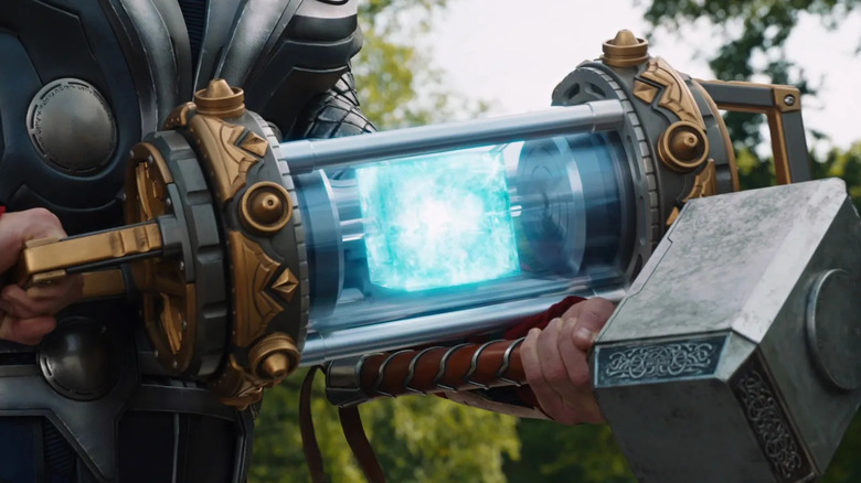 The Tesseract in a container held by Thor next to Mjolnir