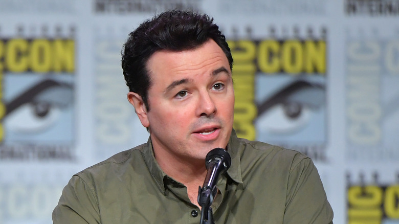 Seth MacFarlane in front of a microphone in a green shirt