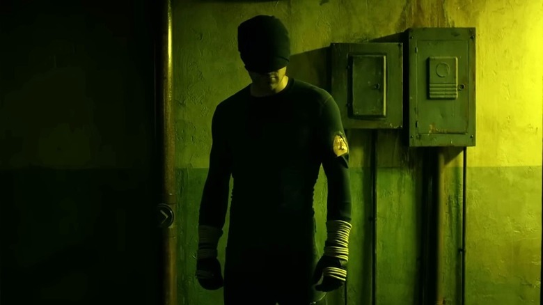 Daredevil standing in a dimly lit hallway wearing a black suit