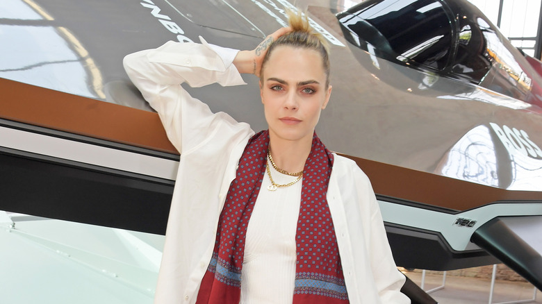 Cara Delevingne smiling, leaning on plane