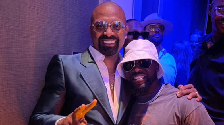 Mike Epps and Kevin Hart smiling together at an event in 2023 with blue and purple lighting