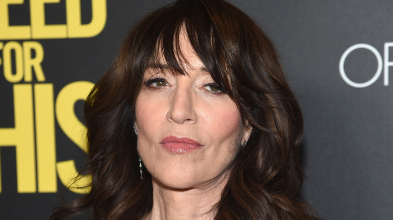 Katey Sagal looking serious in front of black background with yellow letters