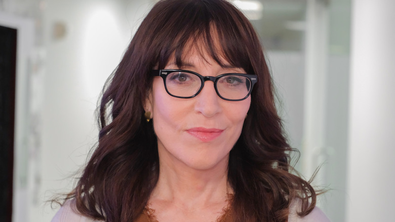 Katey Sagal wearing black glasses staring straight ahead with a closed small smile