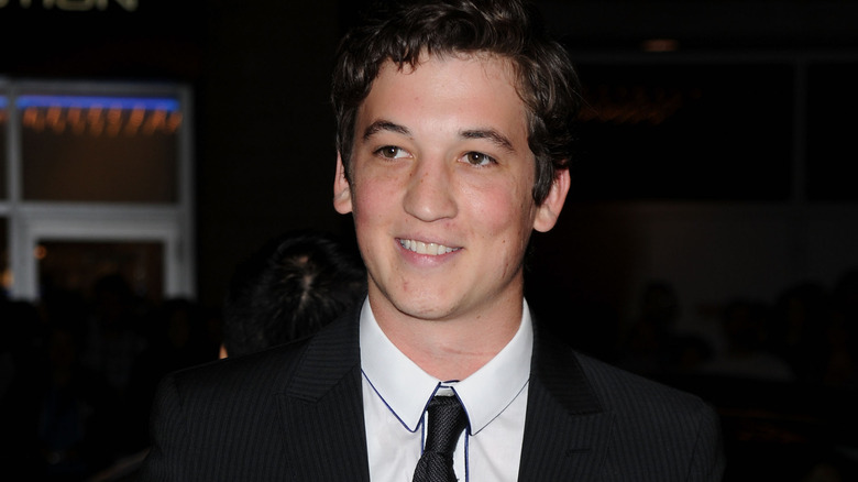 Miles Teller smiling wearing suit