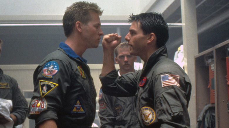 Iceman looking angry at Maverick, who has his fist raised, as another man looks on, in 1986's "Top Gun"