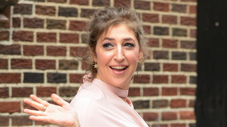 Mayim Bialik waving behind her