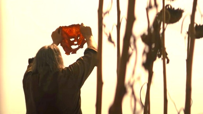 Leatherface holding up a mask of human skin in Texas Chainsaw Massacre