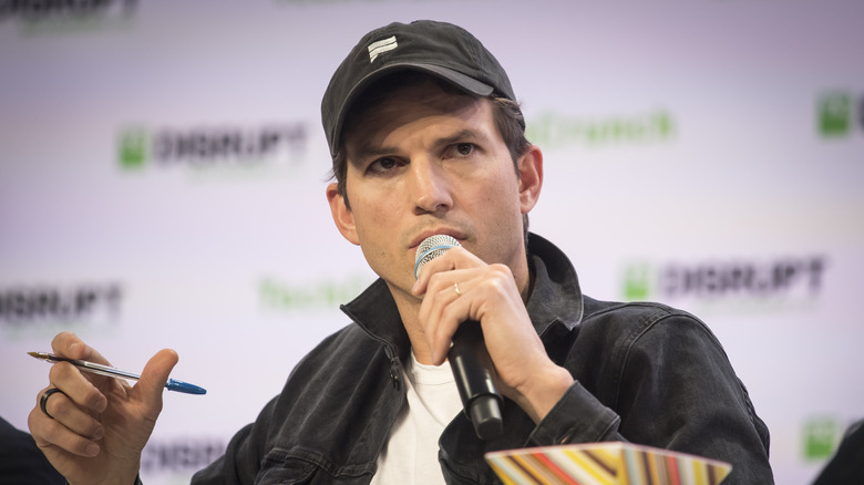 Kutcher speaking holding pen and microphone