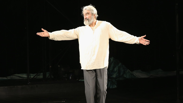 Sam Waterston on stage with arms outstretched as Prospero in The Tempest