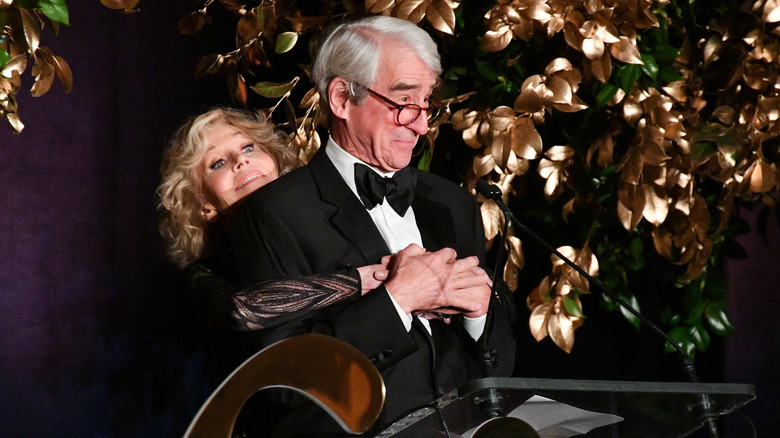 Jane Fonda hugs Sam Waterston at a podiaum