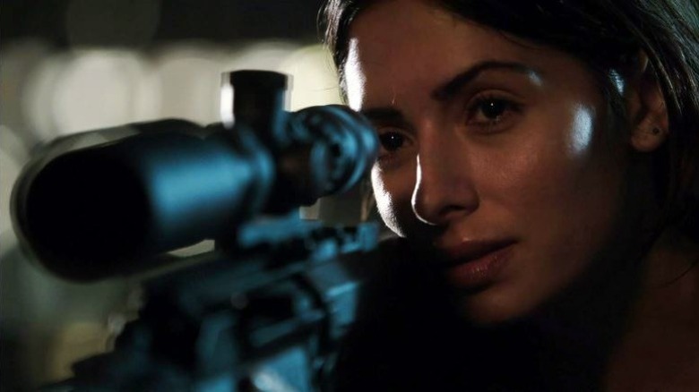 Sameen Shaw looking through a rifle scope