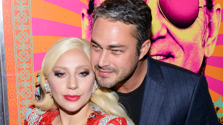 Taylor Kinney leaning into Lady Gaga