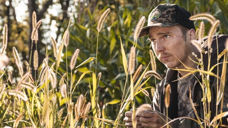 David Sweat crouching to hide among tall grass and reeds in "Escape at Dannemora" (2018)