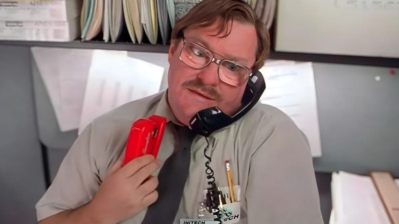 Milton holding a red stapler