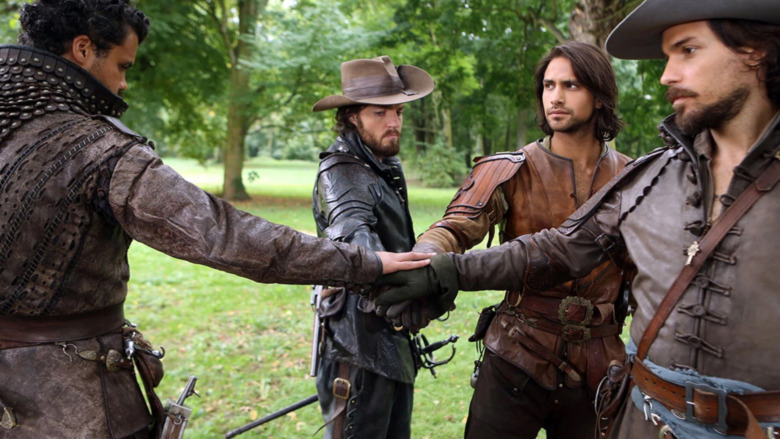 The Musketeers put their hands in a circle