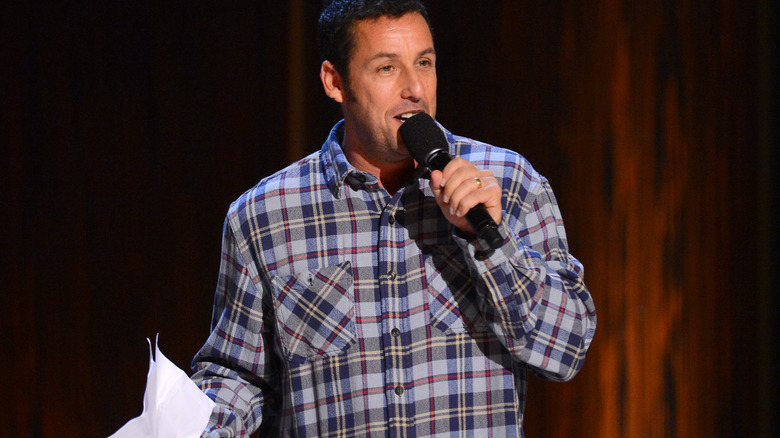 Adam Sandler holding mic and paper