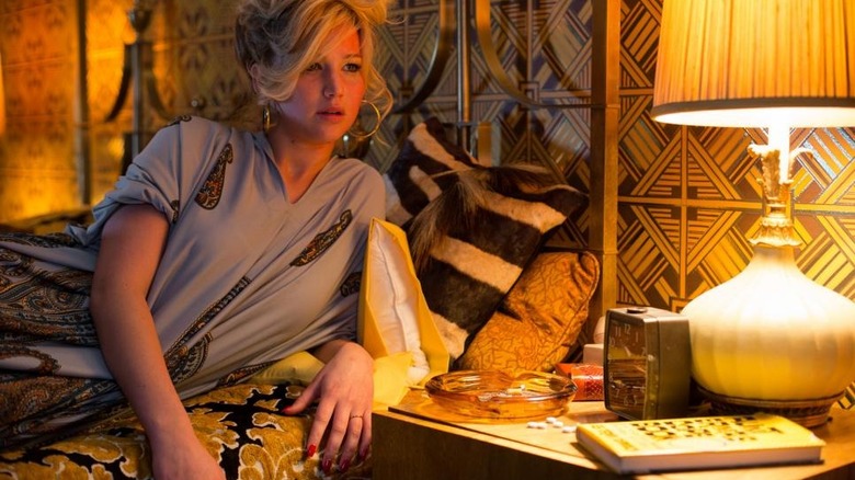 Jennifer Lawrence in golden bed beside night stand