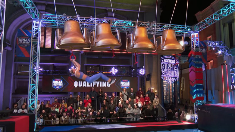 Contestant swinging on bell obstacle