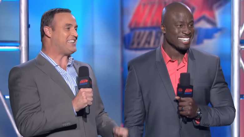 Matt Iseman and Akbar Gbajabiamila holding mics in suits