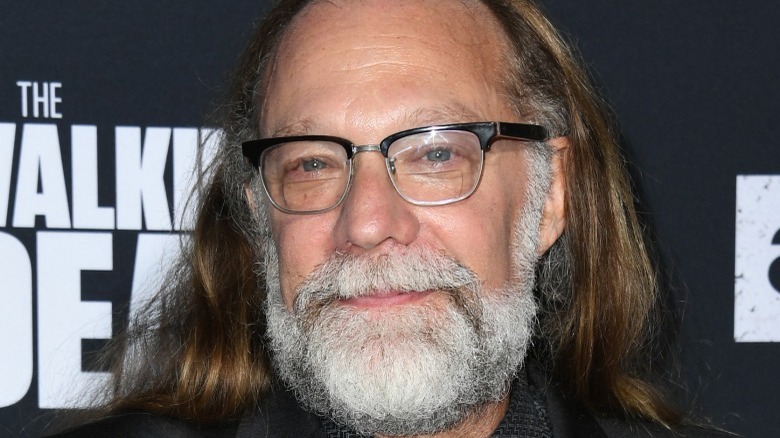 Greg Nicotero smiling in a black suit and glasses