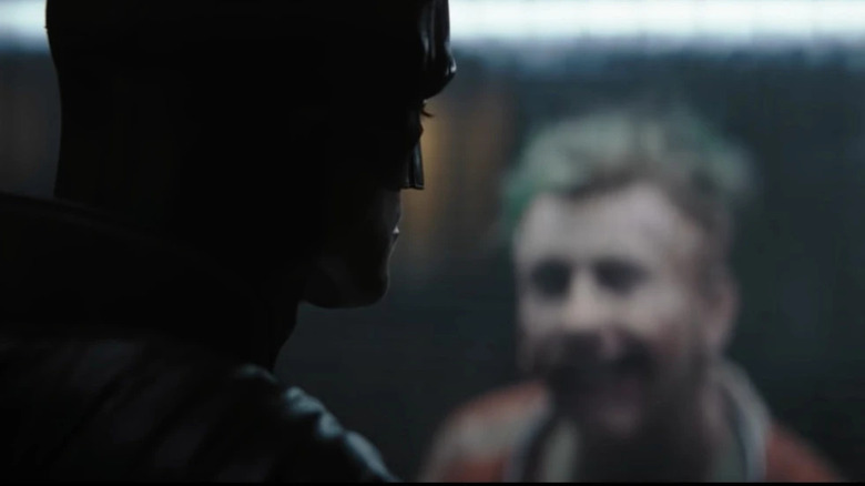 Batman and The Joker talk in prison with a glass wall separating them