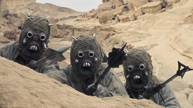 Tusken Raiders peer over the sand