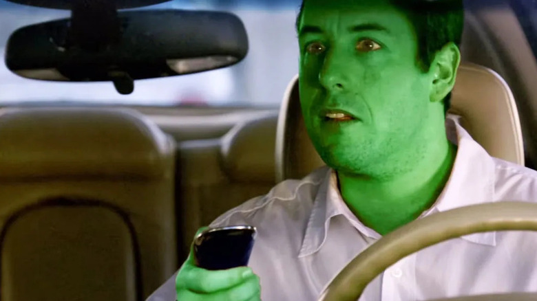 Michel looking in his car's rear-view mirror after making his skin turn green