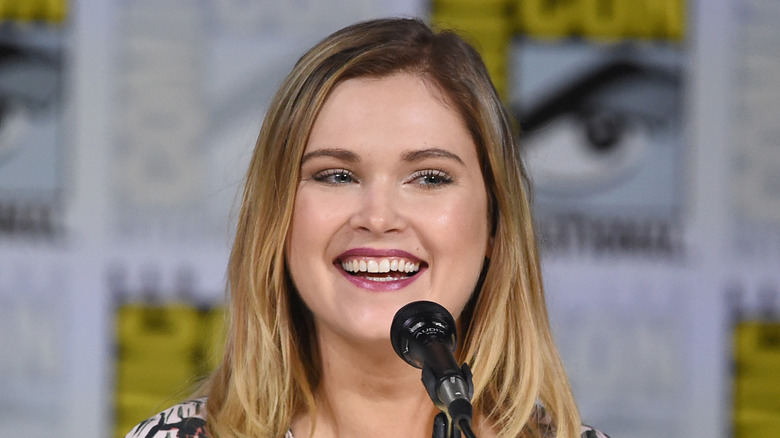 Eliza Taylor smiles in front of microphone