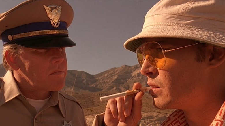 The highway patrolman confronts Hunter S. Thompson, who looks to the horizon with a cigarette in his mouth