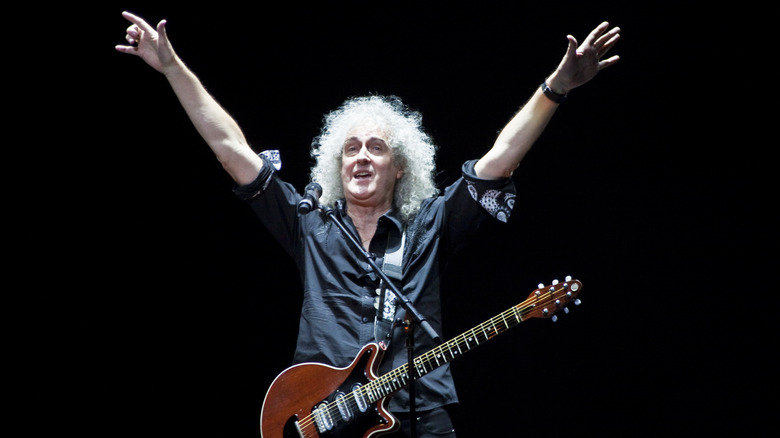 Brian May lifts arms onstage