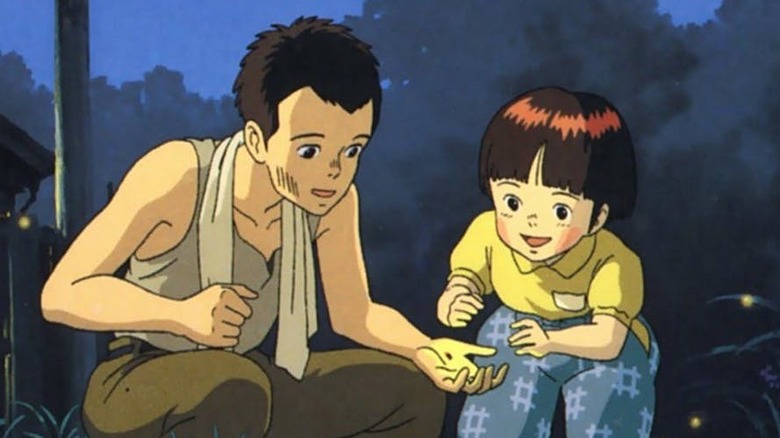 Seita holding a firefly in his hand next to Satsuka 